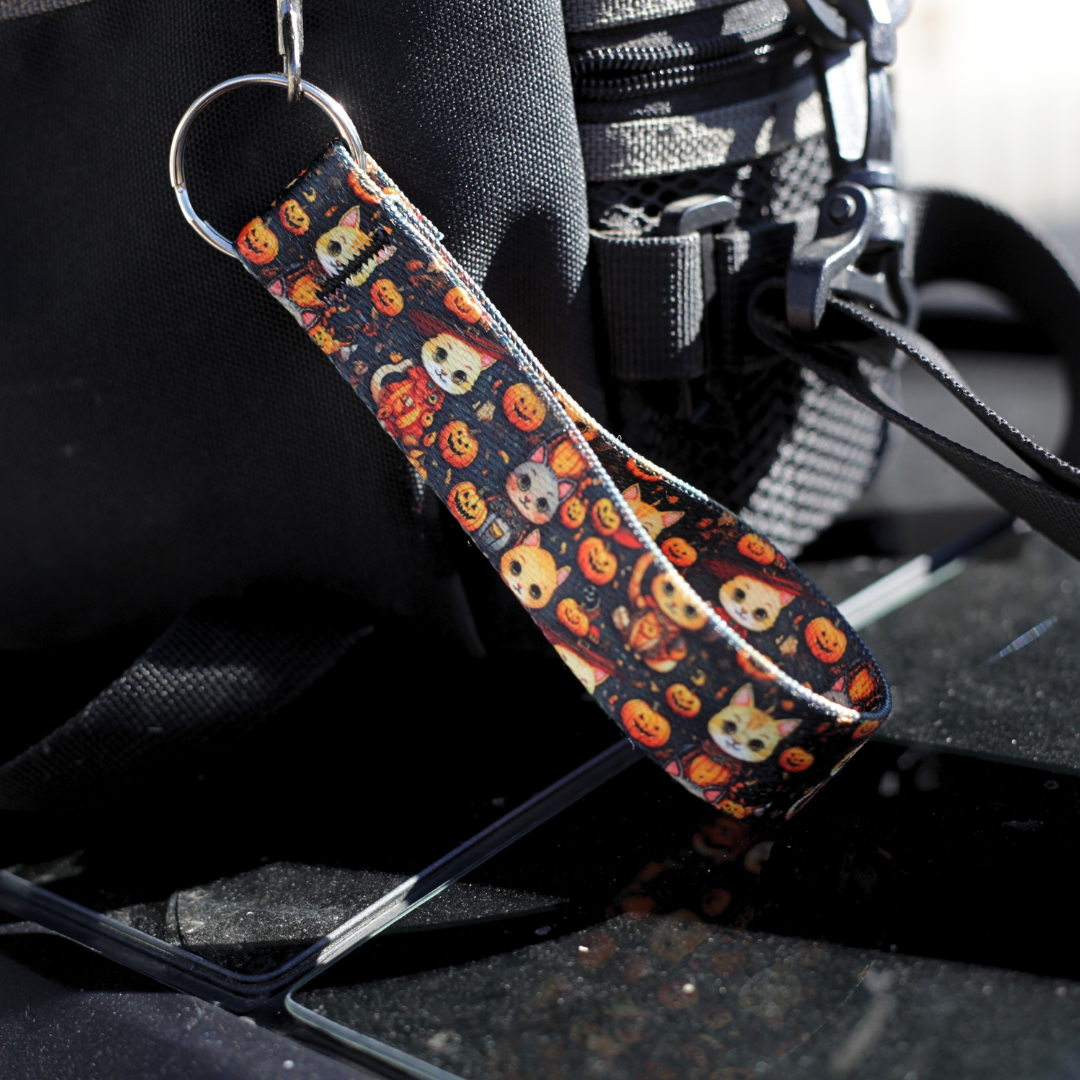 Halloween cat-themed keychain wrist lanyard with pumpkins and spooky designs on black webbing.