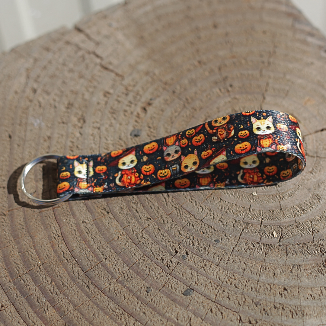 Halloween cat-themed keychain wrist lanyard with pumpkins and spooky designs on black webbing.